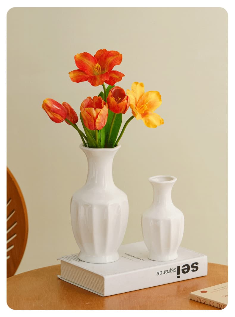 White ceramic vase trio with orange flowers on a small display block