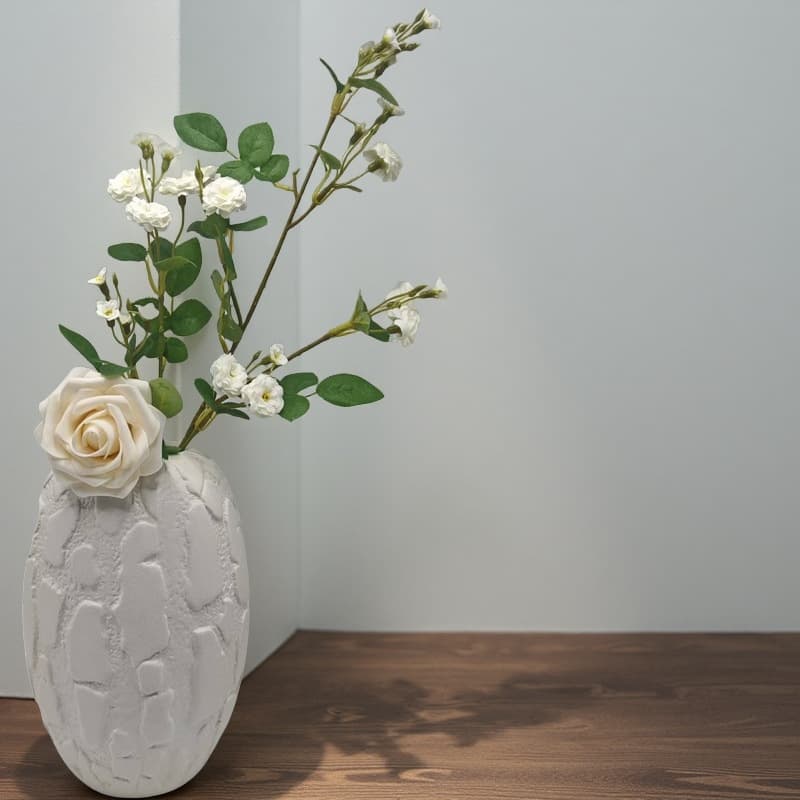 White relief ceramic vase styled with a branch on a wooden table