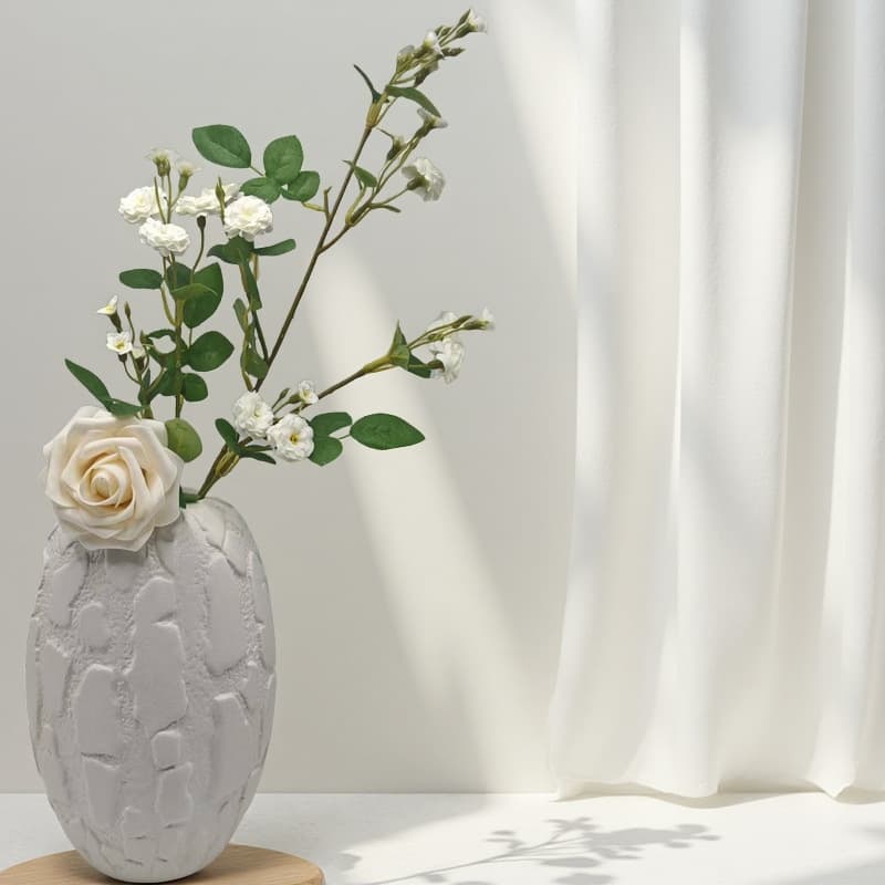 White relief ceramic vase with a single pale rose stem