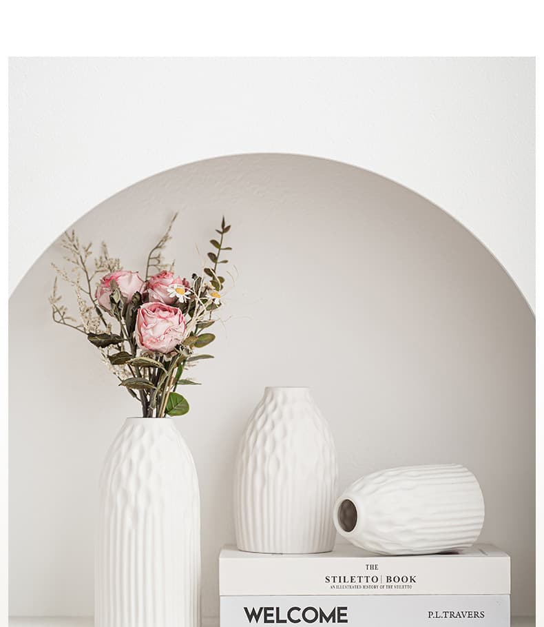 White ribbed ceramic vase set displayed with soft pink flowers