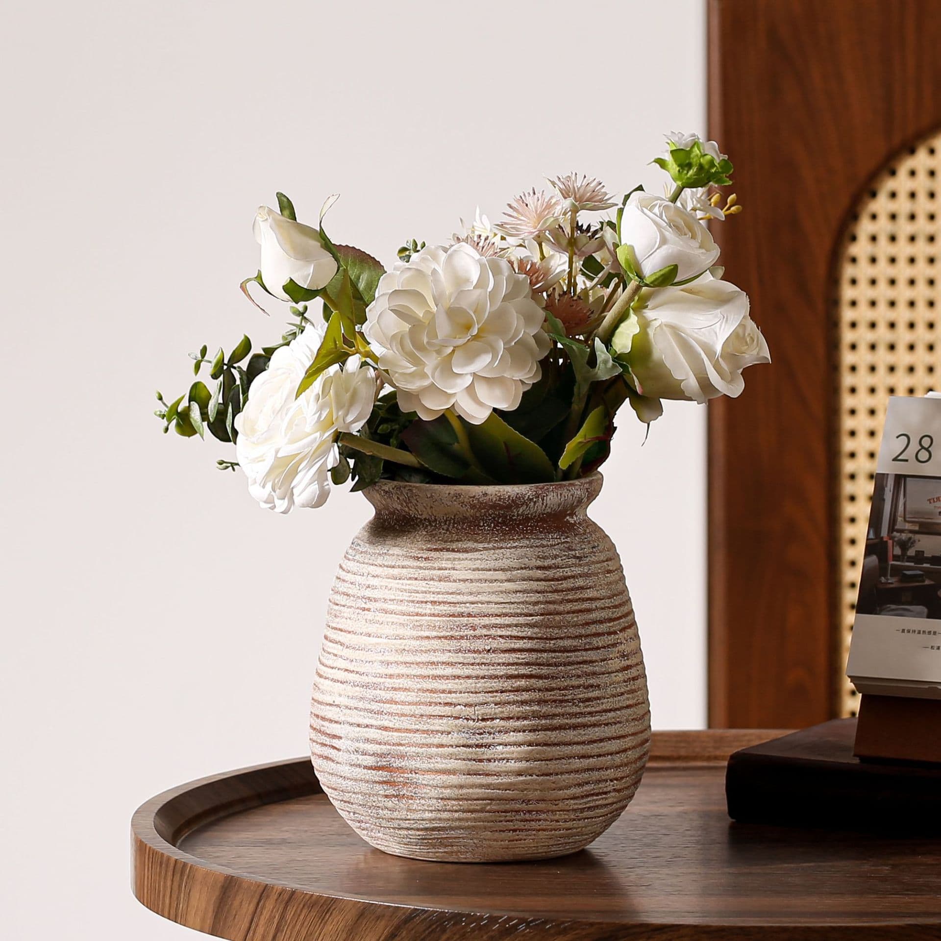 Horizontal ribbed ceramic vase with white flowers on a side table