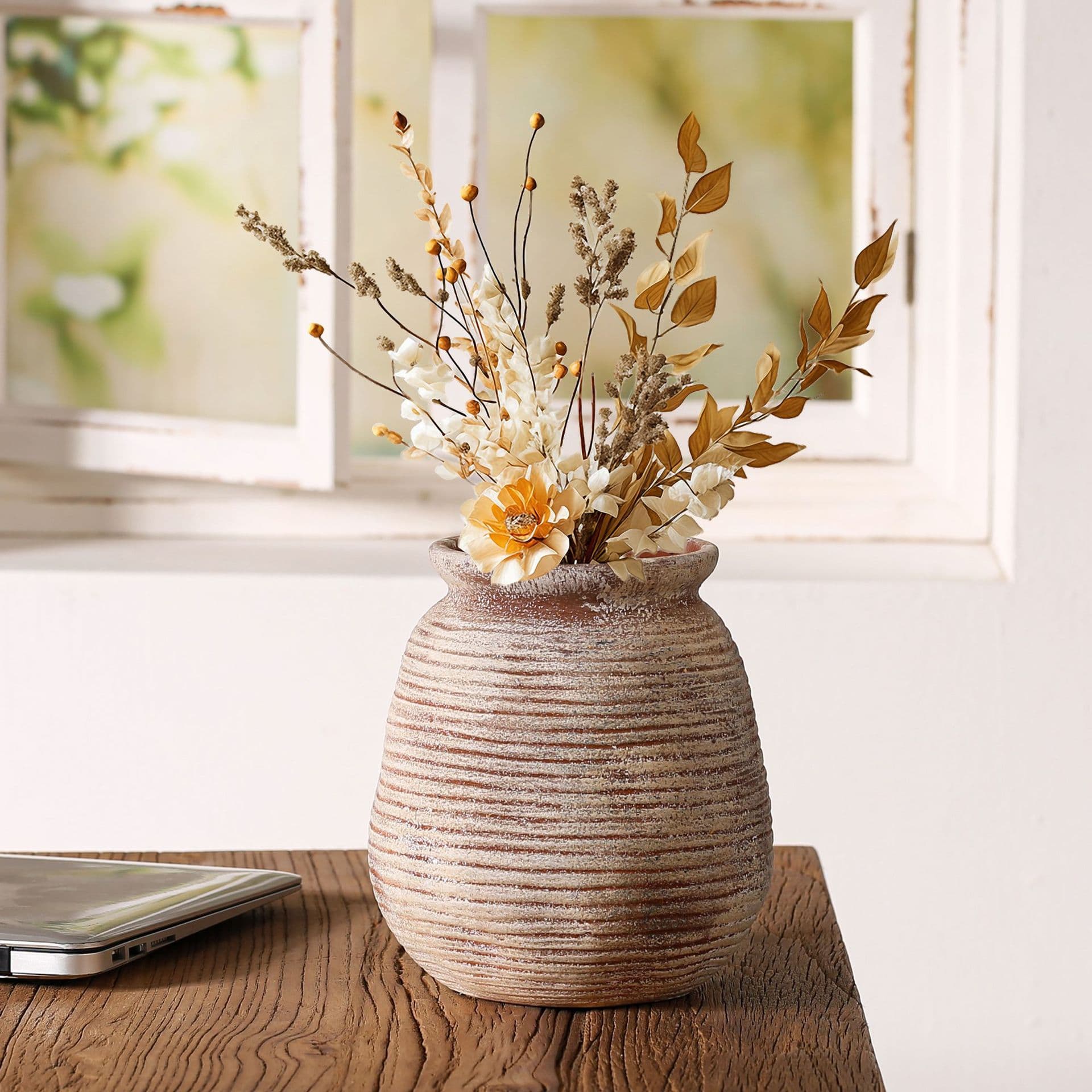 Horizontal ribbed ceramic vase with dried stems by a window